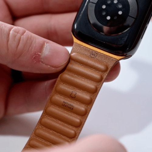 Bracelet Leather Link Apple Watch tenu à la main, dos du bracelet visible avec la mention cuir naturel